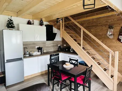 a kitchen with a table and a staircase in a room at La Tanière in Samoëns