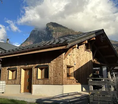 a wooden house with a mountain in the background at La Tanière in Samoëns