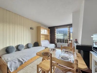 a room with a bed and a table with chairs at MOU2E Studio 4 Pers centre des Carroz in Les Carroz d'Araches