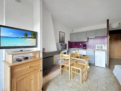 a kitchen and dining room with a table and a television at MOU2E Studio 4 Pers centre des Carroz in Les Carroz d'Araches