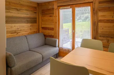 a living room with a couch and a table and a window at Le Cocon Des Pistes in Saint-Gervais-les-Bains