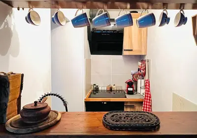 a kitchen with a wooden table with cups hanging from the ceiling at Chez moi in Chamonix-Mont-Blanc