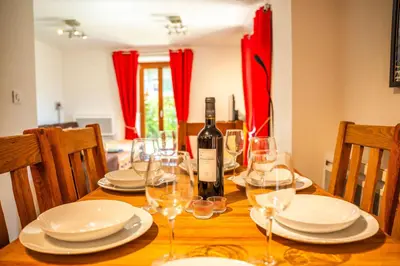 a wooden table with a bottle of wine and glasses at 3 bed apt,central location, parking, garden, 6 pax in Saint-Gervais-les-Bains