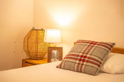 a bed with a pillow and a lamp on a table at 3 bed apt,central location, parking, garden, 6 pax in Saint-Gervais-les-Bains