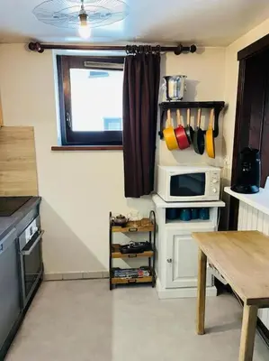 a small kitchen with a microwave and a table at Duplex Le géant 7 voyageurs in Chamonix-Mont-Blanc