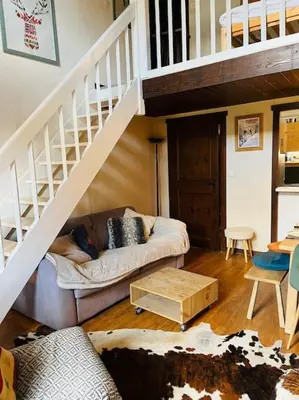 a living room with a couch and a staircase at Duplex Le géant 7 voyageurs in Chamonix-Mont-Blanc
