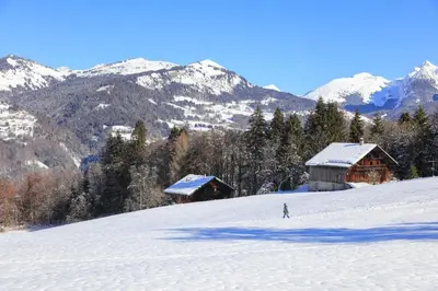 a person skiing down a snow covered slope with buildings at Les Eterlous 28 - Appt montagne 4 pers in Morillon