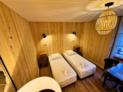 a room with two beds and a chandelier at Appartement Chamonix Centre - Vue Mont Blanc in Chamonix-Mont-Blanc