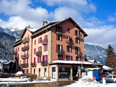 a large building with pink doors and windows in the snow at Appartement Chamonix Centre - Vue Mont Blanc in Chamonix-Mont-Blanc