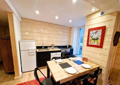 a kitchen with a table and a white refrigerator at Appartement Chamonix Centre - Vue Mont Blanc in Chamonix-Mont-Blanc