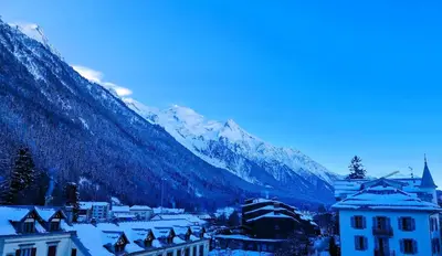 a town with snow covered mountains in the background at Appartement Chamonix Centre - Vue Mont Blanc in Chamonix-Mont-Blanc