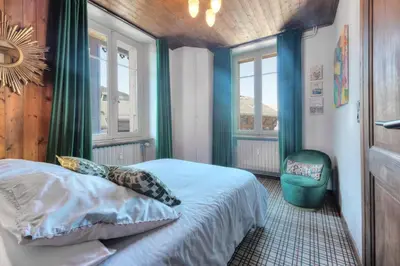 a bedroom with a bed and a chair and windows at Tatiana I in Megève