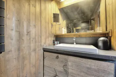 a bathroom with a white sink and wooden walls at Tatiana I in Megève