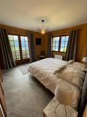 a bedroom with a large bed and windows at Chalet de la buche croisée in Combloux