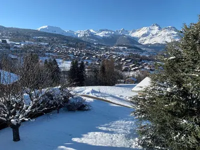 a snow covered city with mountains in the background at Chalet de la buche croisée in Combloux