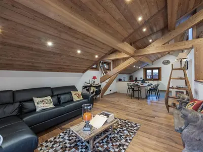 a living room with a black leather couch and wooden ceilings at Appartement rénové au centre de Megève avec balcon et parking - FR-1-569-137 in Megève