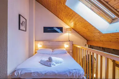 a person laying on a bed in a room at Chamour - A duplex apartment with Mont-Blanc view in Chamonix-Mont-Blanc