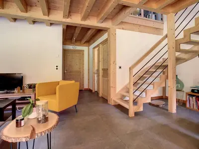 a living room with a staircase and a yellow chair at Le Vivier in Saint-Gervais-les-Bains