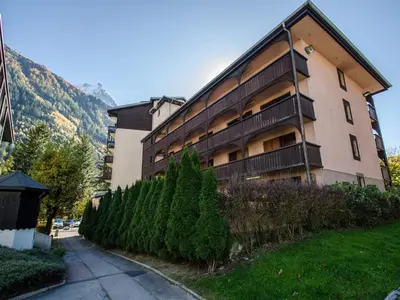 a large building with a fence next to a street at Appartement cosy à Chamonix pour 4, balcon, parking - FR-1-343-250 in Chamonix-Mont-Blanc