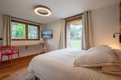 a bedroom with a bed and a window and a red chair at Chalets ASA 426 m2 in Chamonix-Mont-Blanc