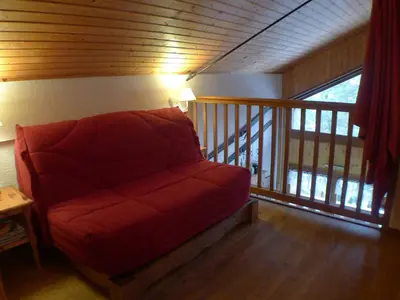 a red couch in a room with a balcony at Appartement 2 pièces avec mezzanine, casier à skis et parking privatif à Samoëns - FR-1-629-135 in Samoëns