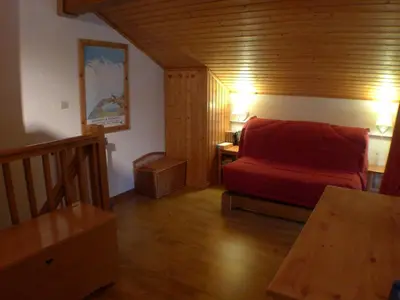 a living room with a red couch and a table at Appartement 2 pièces avec mezzanine, casier à skis et parking privatif à Samoëns - FR-1-629-135 in Samoëns