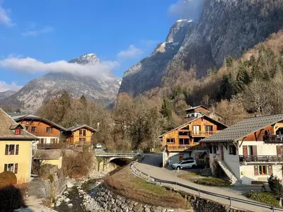 a village with houses and a bridge and mountains at Appartement 2 pièces avec mezzanine, casier à skis et parking privatif à Samoëns - FR-1-629-135 in Samoëns