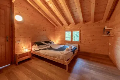 a bedroom with a bed in a log cabin at Chalet aux Cerfs - Maison pour 10 vue montagne in Arâches-la-Frasse