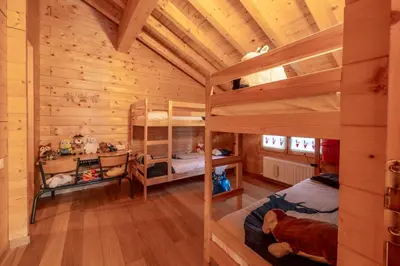 a bedroom with two bunk beds in a log cabin at Chalet aux Cerfs - Maison pour 10 vue montagne in Arâches-la-Frasse