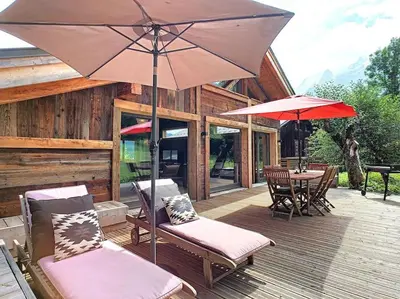 a patio with a table and chairs and an umbrella at A 2 min du télécabine Chalet de charme 4 étoiles in Les Houches