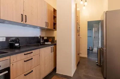 a kitchen with wooden cabinets and a stainless steel refrigerator at Majestic - Appartement 2 pas du centre-ville Chamo in Chamonix-Mont-Blanc