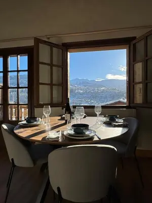 a table with chairs and wine glasses and a large window at Chalet LE REPAIRE proches des Pistes in Megève