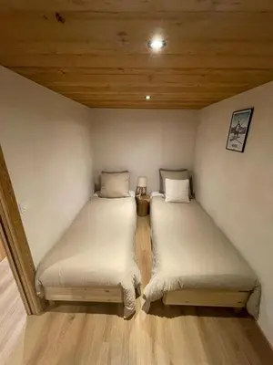 two twin beds in a room with wooden ceilings at Chalet LE REPAIRE proches des Pistes in Megève