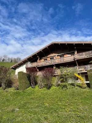 a building on a hill with a green field at Chalet LE REPAIRE proches des Pistes in Megève