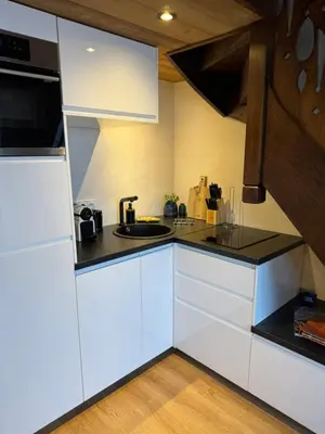 a kitchen with white cabinets and a black counter top at Chalet LE REPAIRE proches des Pistes in Megève