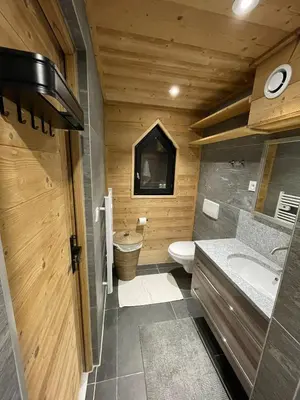 a wooden bathroom with a toilet and a sink at Très bel appartement spacieux in Les Carroz d'Araches