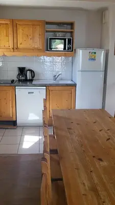 a kitchen with a table and a white refrigerator at Next to the ski lift! *3bed Apt* sleeps 8* Parking* Pool in Saint-Gervais-les-Bains
