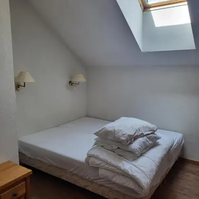 a bedroom with a bed with white sheets and a window at Next to the ski lift! *3bed Apt* sleeps 8* Parking* Pool in Saint-Gervais-les-Bains