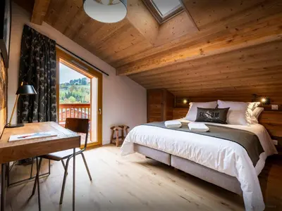 a bedroom with a bed and a desk and a window at Le Primpiolet - OVO Network in Combloux