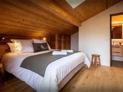 a bedroom with a large bed with wooden ceilings at Le Primpiolet - OVO Network in Combloux
