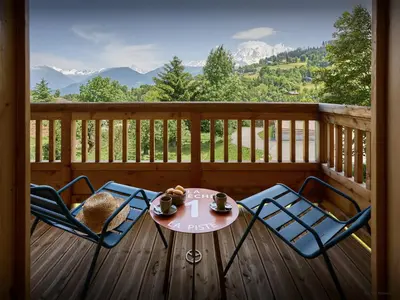a table and chairs on a deck with a view of mountains at Le Primpiolet - OVO Network in Combloux