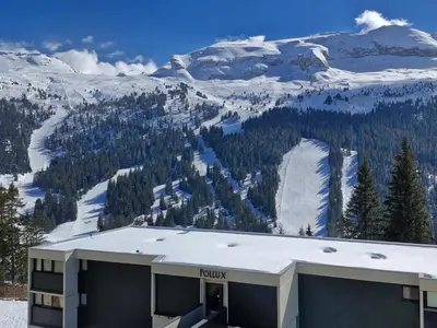 a building with a snow covered mountain in the background at Studio rénové à Flaine · Balcon Sud · Idéal pour 4 personnes - FR-1-425-209 in Arâches-la-Frasse