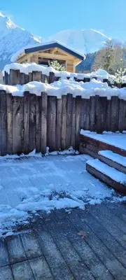 a wooden fence in front of a house with snow at Les petites chambres St Gervais in Saint-Gervais-les-Bains