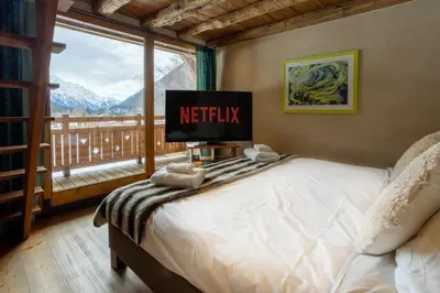 a bedroom with a bed with a tv and a window at Chalet Melusine - Big Chalet w Spa Pool, Sauna, Huge Terrace, Views & Privacy! in Argentiere