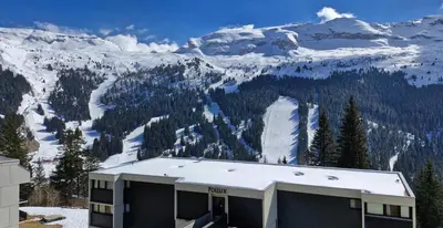a building with a snow covered mountain in the background at Résidence Gemeaux - Studio rénové · Centre station · Balcon MAE-0491 in Magland