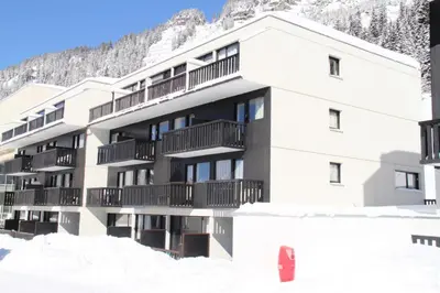 a building in the snow with a mountain in the background at Résidence Gemeaux - Studio rénové · Centre station · Balcon MAE-0491 in Magland