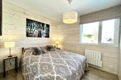 a bedroom with wooden walls and a bed with pillows at Le Balcon des Princesses in Demi-Quartier
