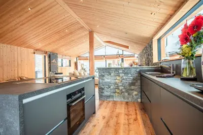 a kitchen with wooden ceilings and a stone wall at Chalet Sia - Contemporain - Sauna prive in Chamonix-Mont-Blanc