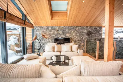a living room with white furniture and a stone wall at Chalet Sia - Contemporain - Sauna prive in Chamonix-Mont-Blanc