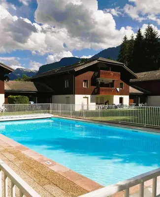 a large blue swimming pool in front of a house at Appartement rénové T2, vue montagne in Samoëns